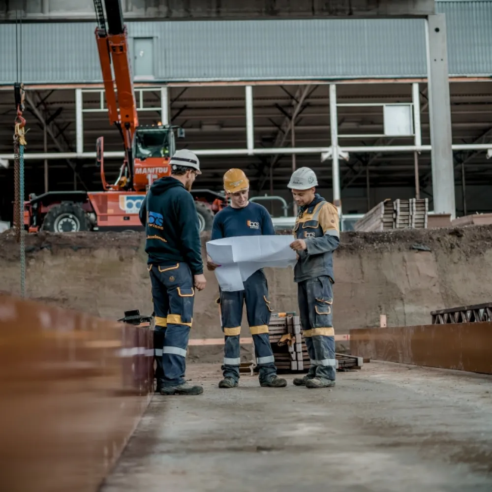 Drie mannen op een werf met plan