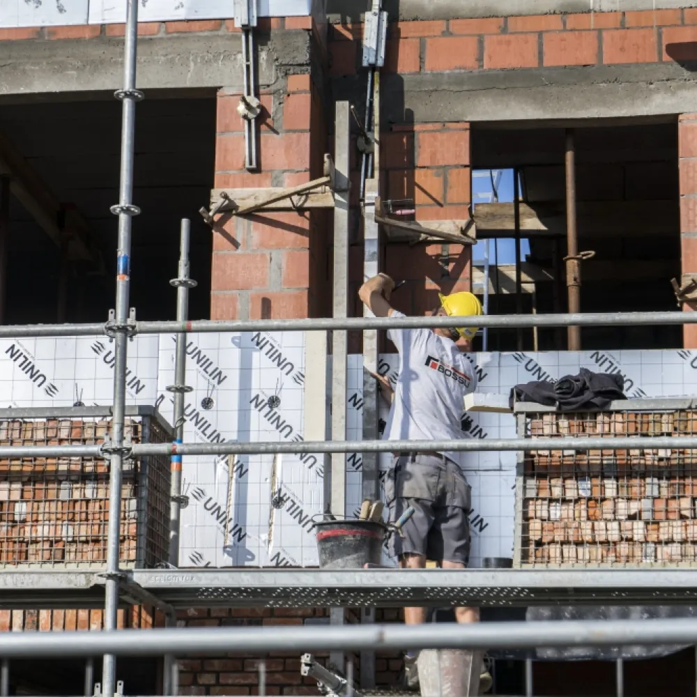 Man staat op stelling en is aan het metsen (ruwbouw)