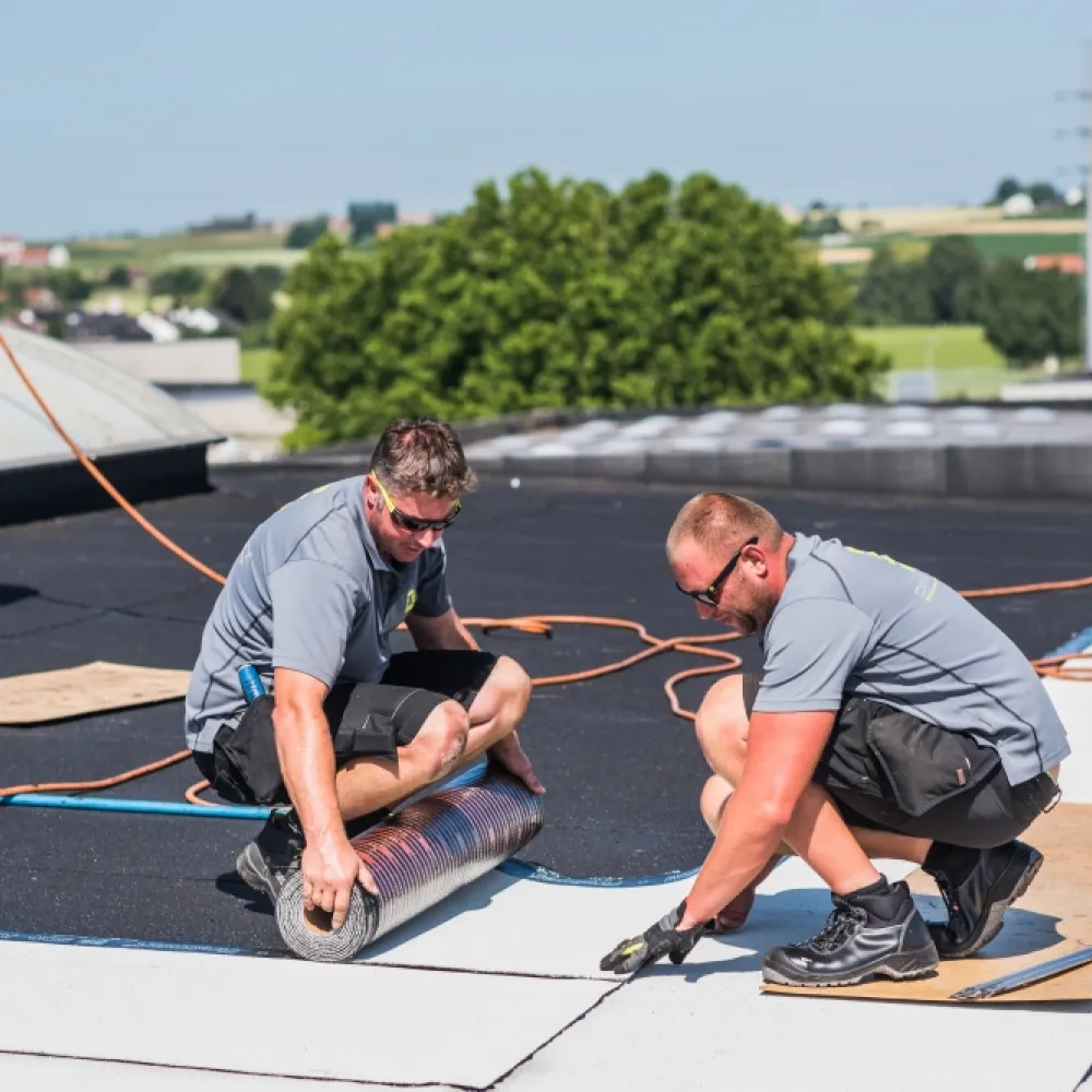 Twee mannen leggen roofing op een dak