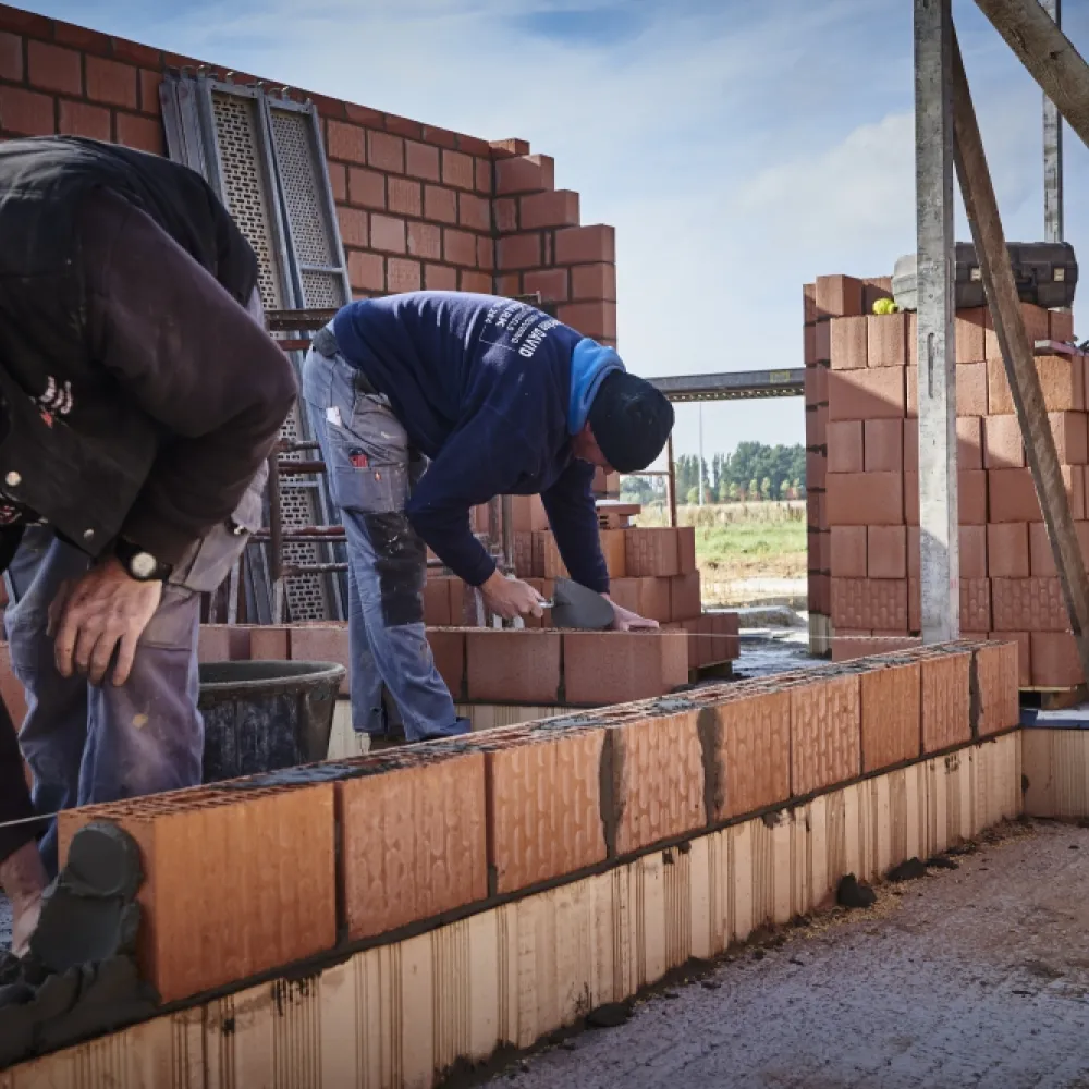 Twee arbeiders metsen een muur (ruwbouw)