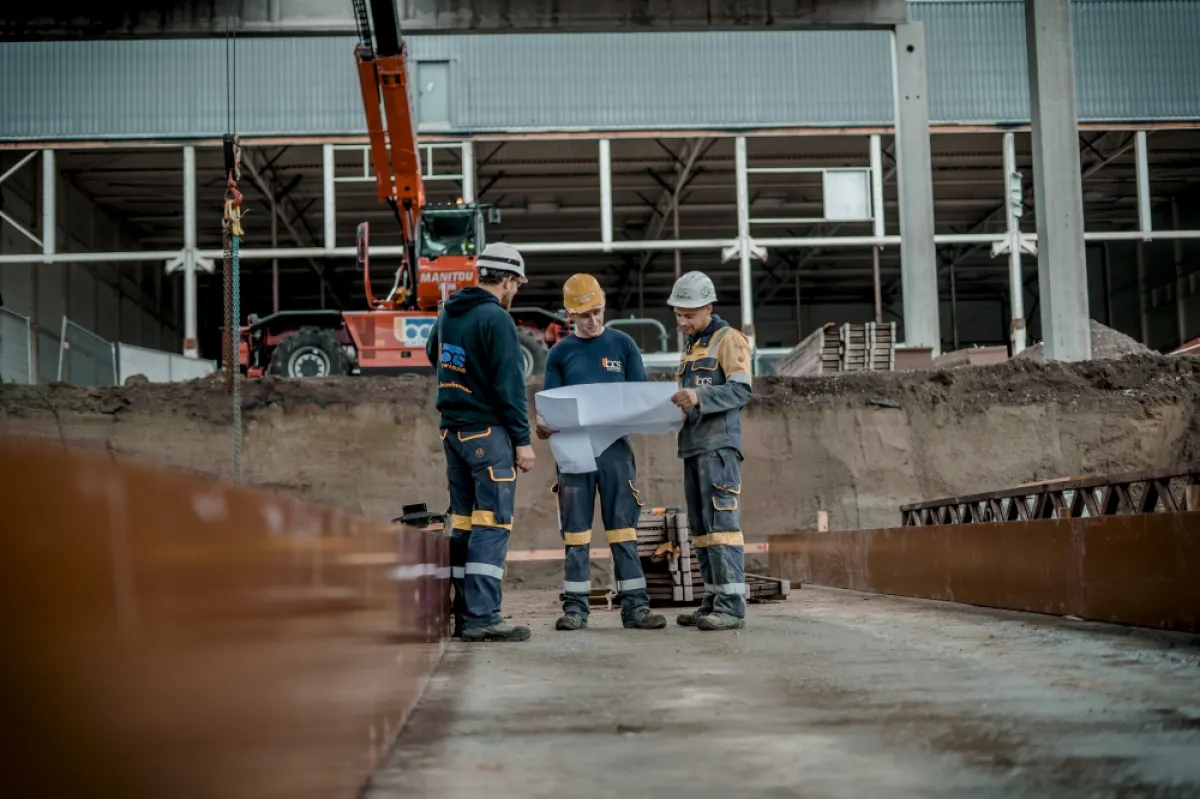 Drie mannen op een werf met plan